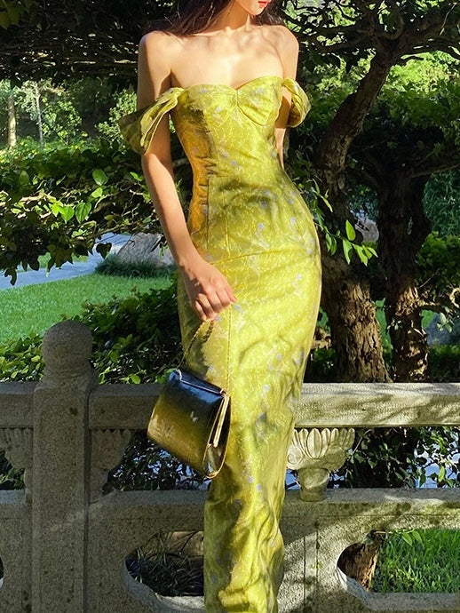 Woman in a green strapless dress holding a black handbag outdoors.