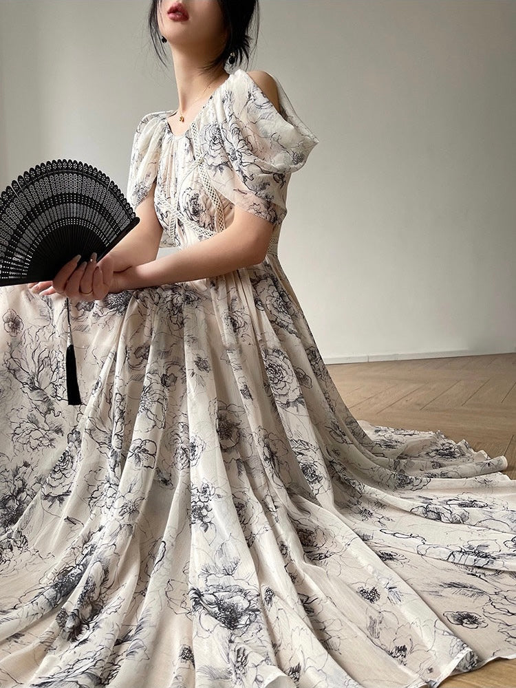 Woman in a floral dress holding a black fan against a plain background