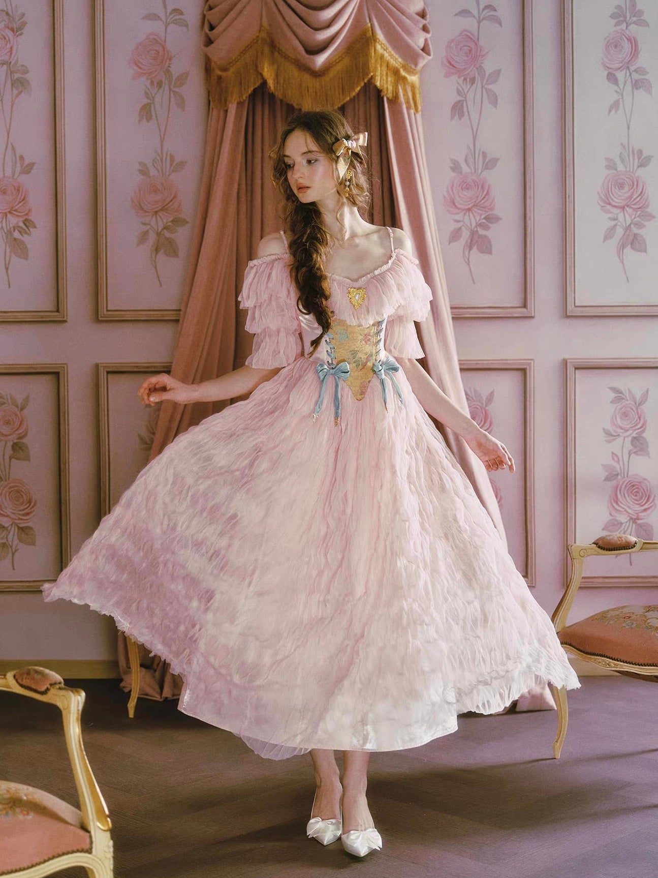 Woman in a vintage-style dress standing in a room with floral wallpaper.