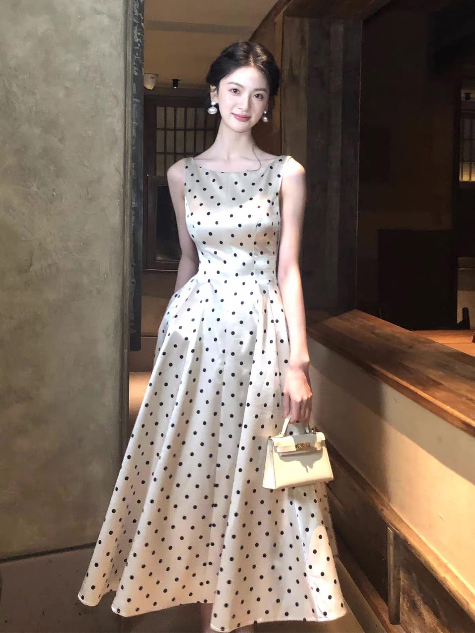 Woman in a polka dot dress standing in an indoor setting