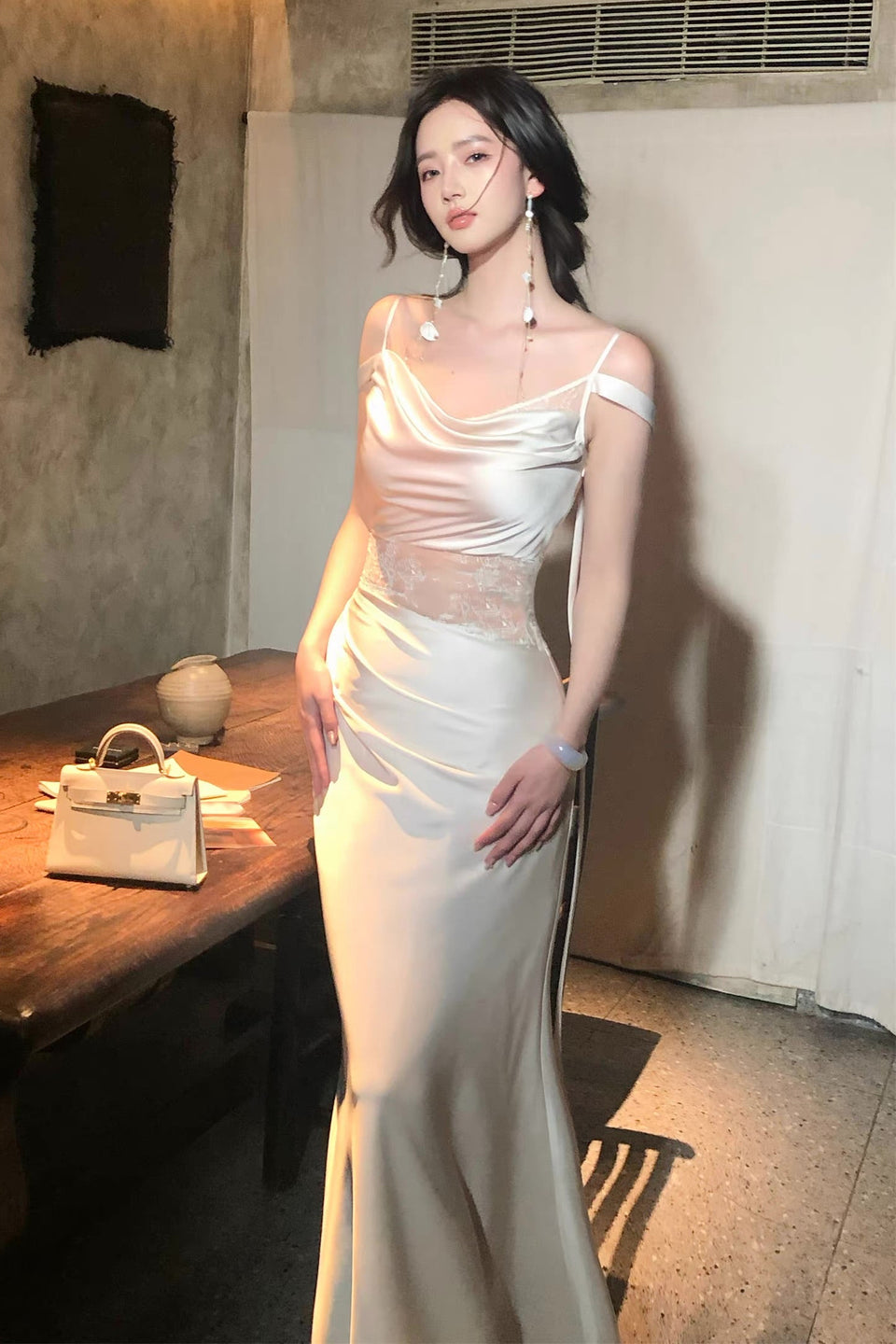 Woman in a white evening gown standing in an indoor setting.