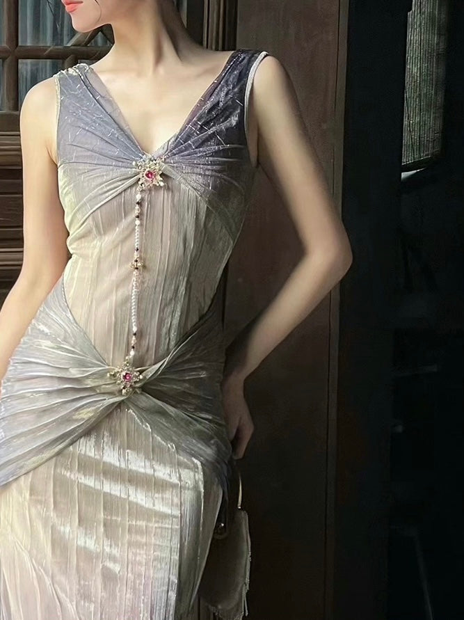 A close-up of a woman wearing a luxurious purple-to-gold gradient dress with a deep V-neckline and a detachable brooch.